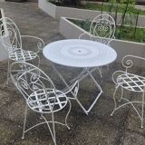 Folding round table and four wrought iron armchairs