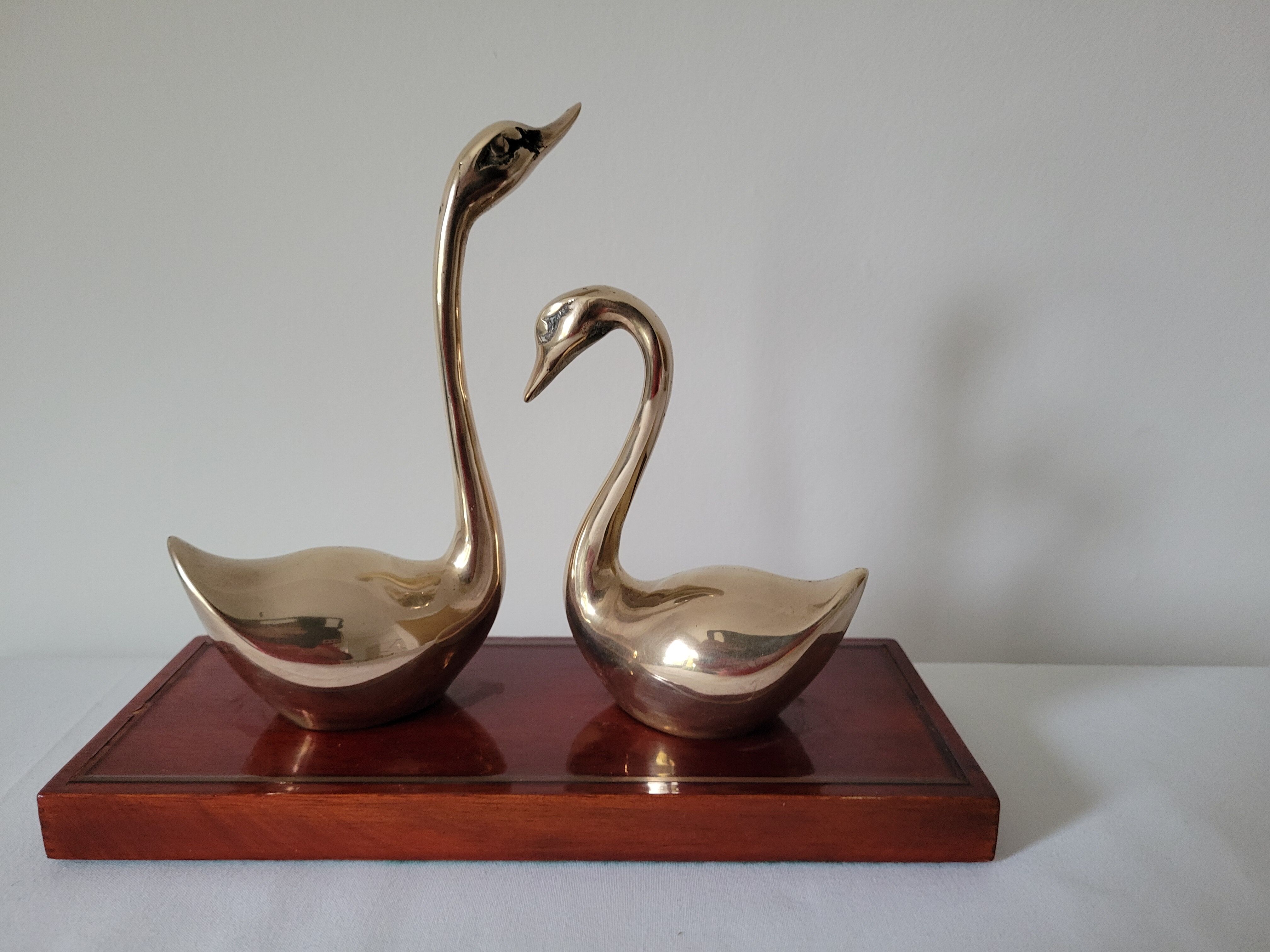 Duo of brass swans on base