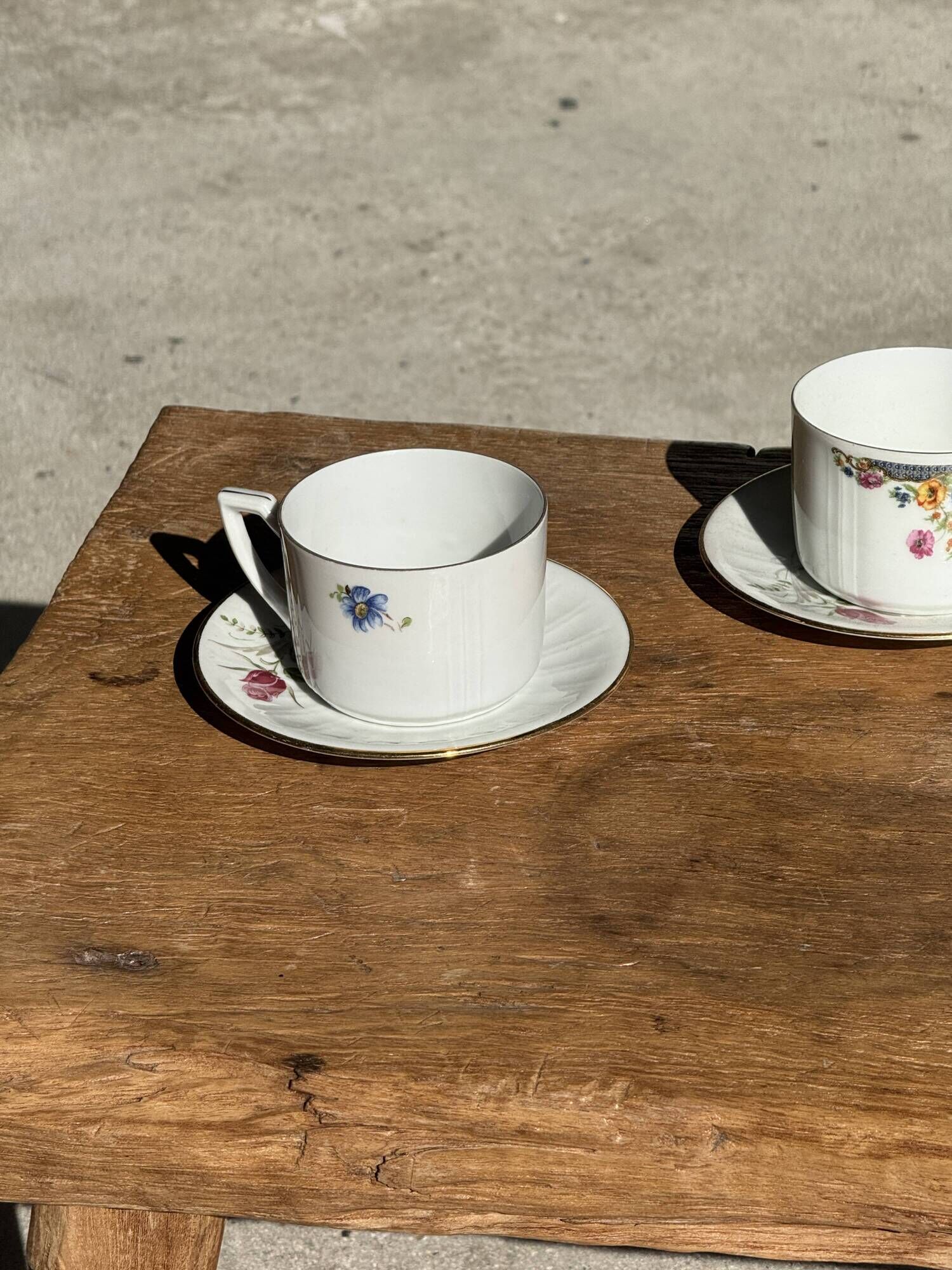 Pair of white porcelain cups from ADP France with a floral pattern and their s