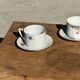 Pair of white porcelain cups from ADP France with a floral pattern and their s