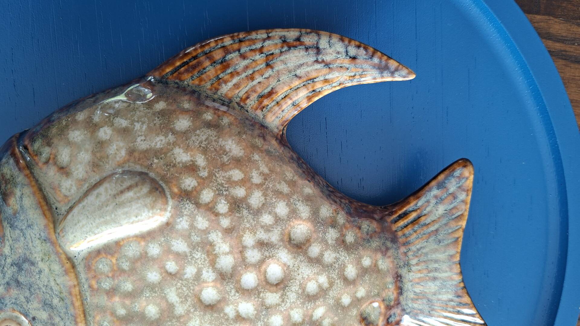 Vallauris ceramic wall sculpture of a relief fish on a blue plaque.