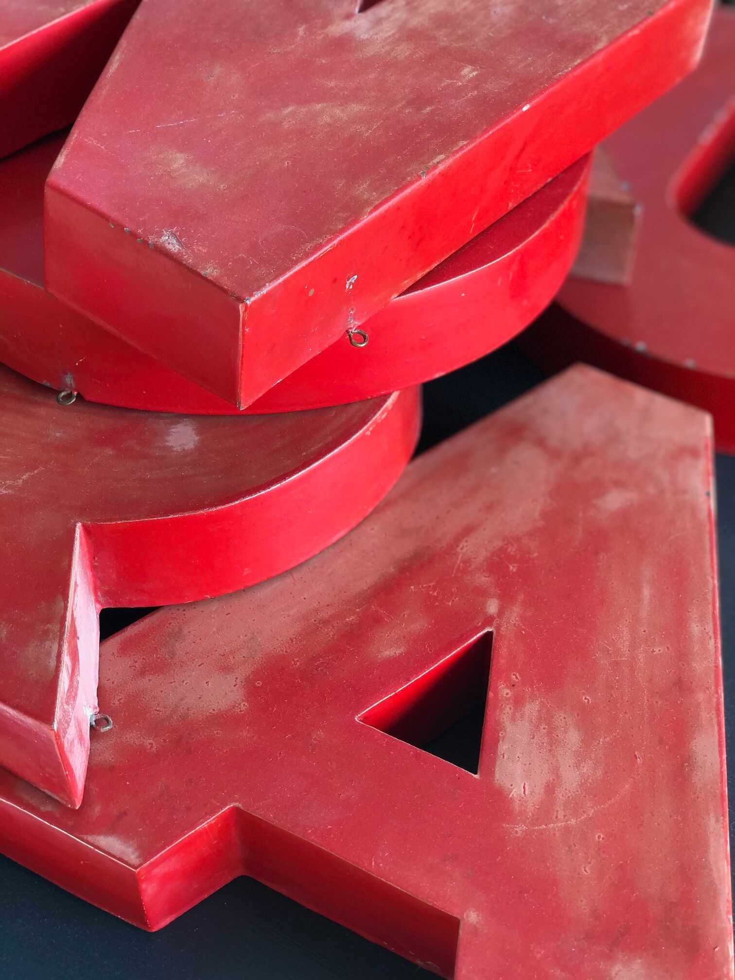 Lettres d'enseigne en zinc rouge formant le mot JOURNAUX