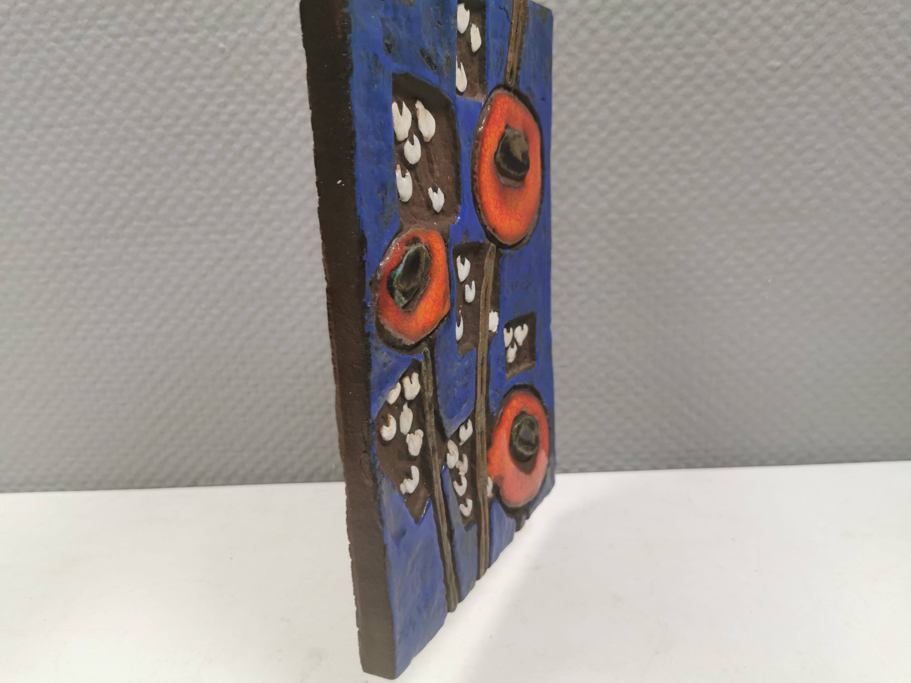 Ceramic relief in attractive blue with a motif of white/red flowers.