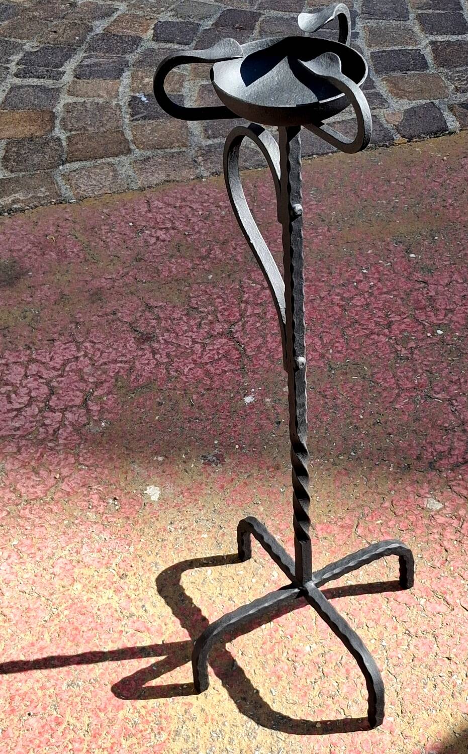 Old ashtray on twisted hammered wrought iron legs, vintage decor.