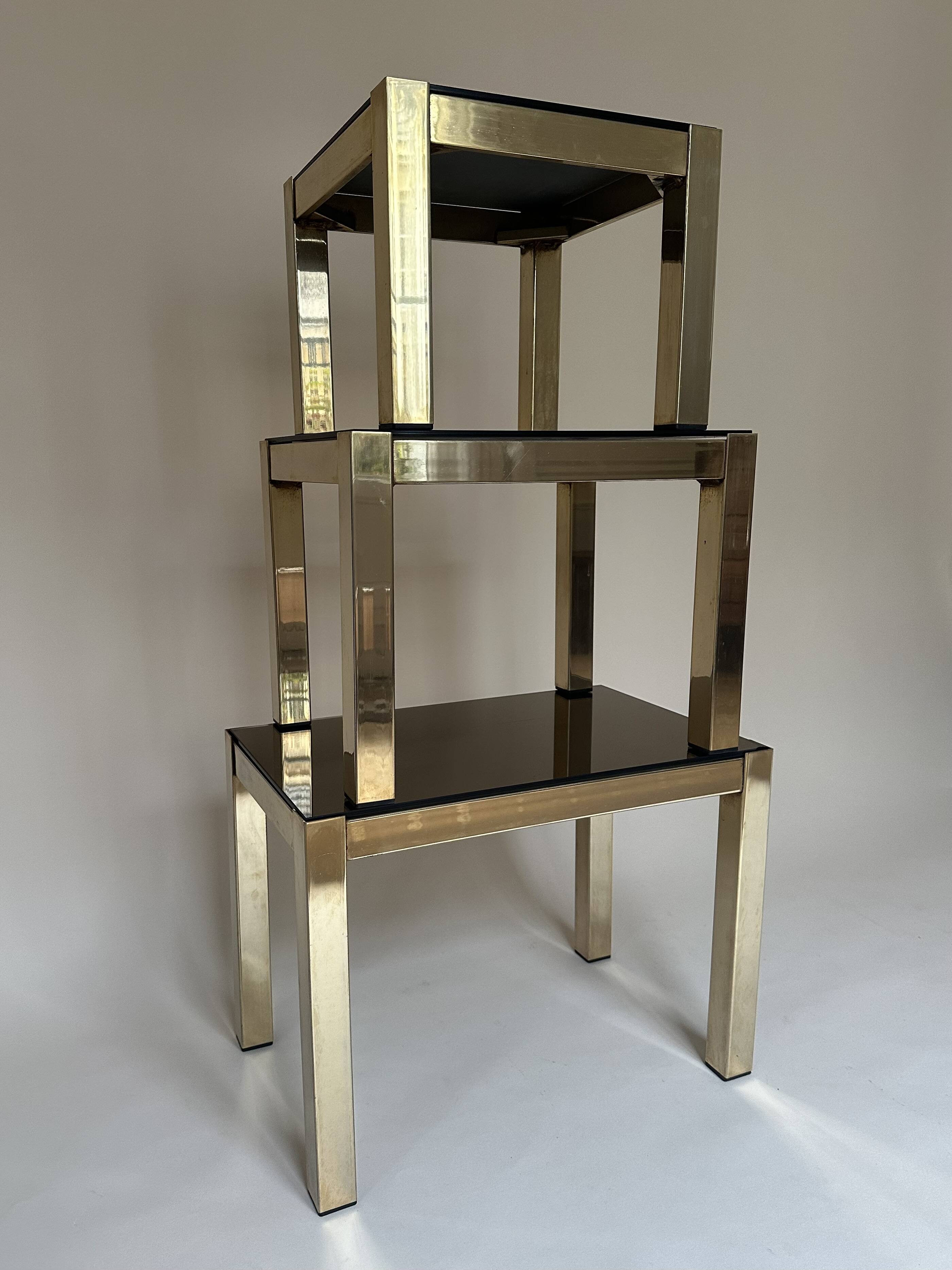 Set of three nesting side tables in brass and smoked mirror.