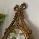 Oval convex witch mirror with golden ribbon mouldings.