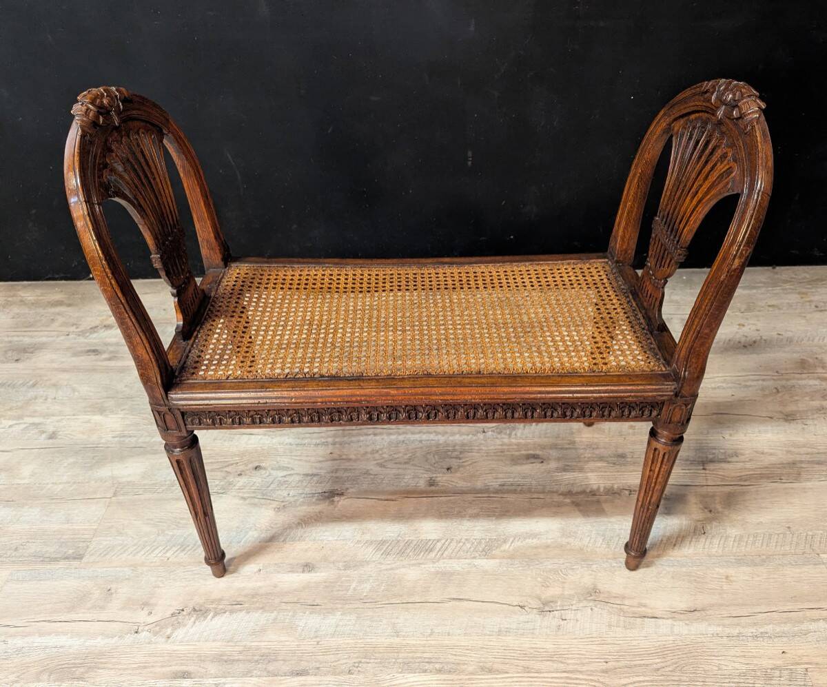 Louis XVI bench in walnut with cane seating.