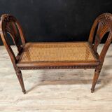 Louis XVI bench in walnut with cane seating.