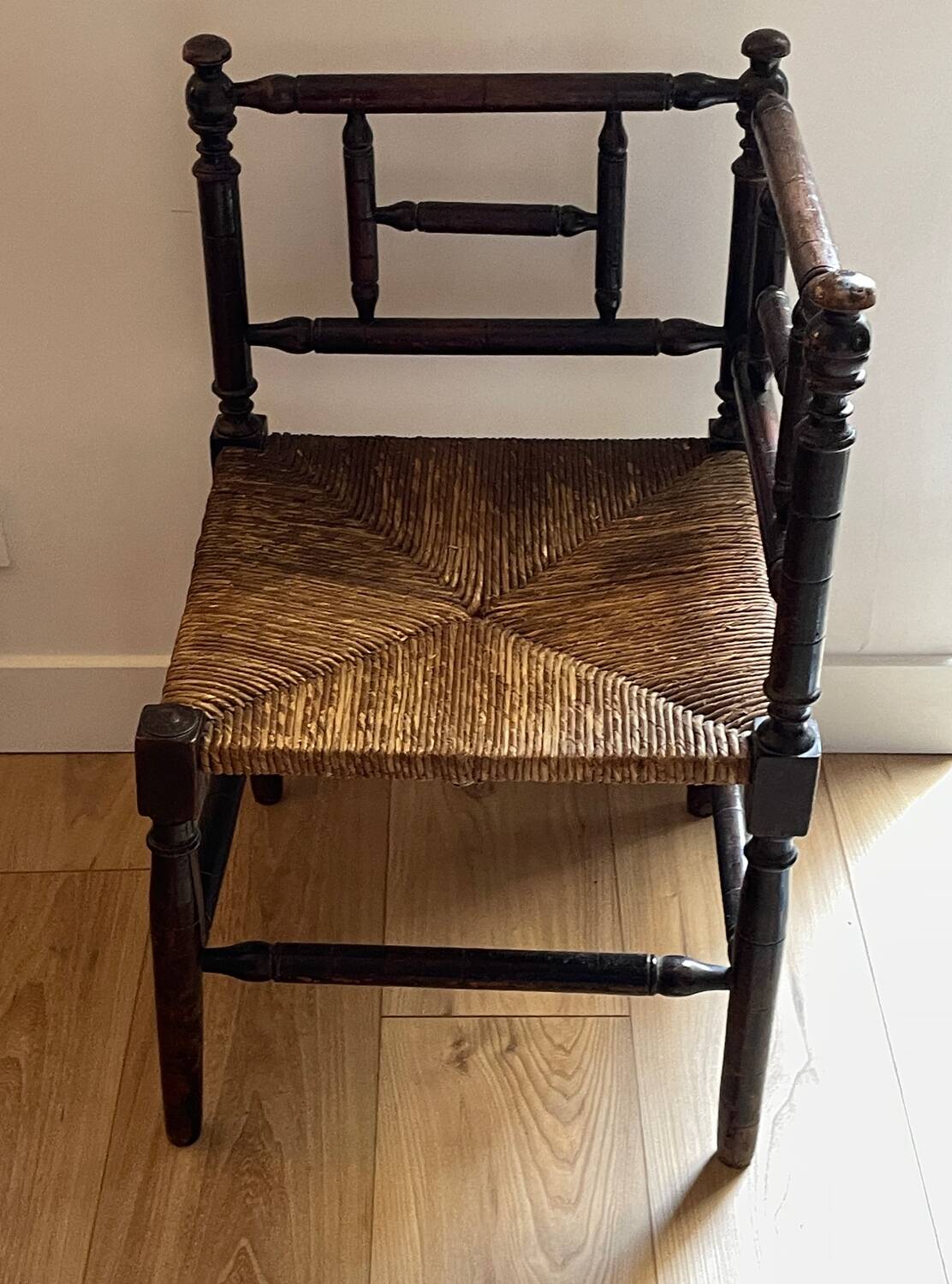 Corner chair made of turned wood with a straw seat.
