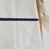 Handwoven throw with black stripes and pom-poms