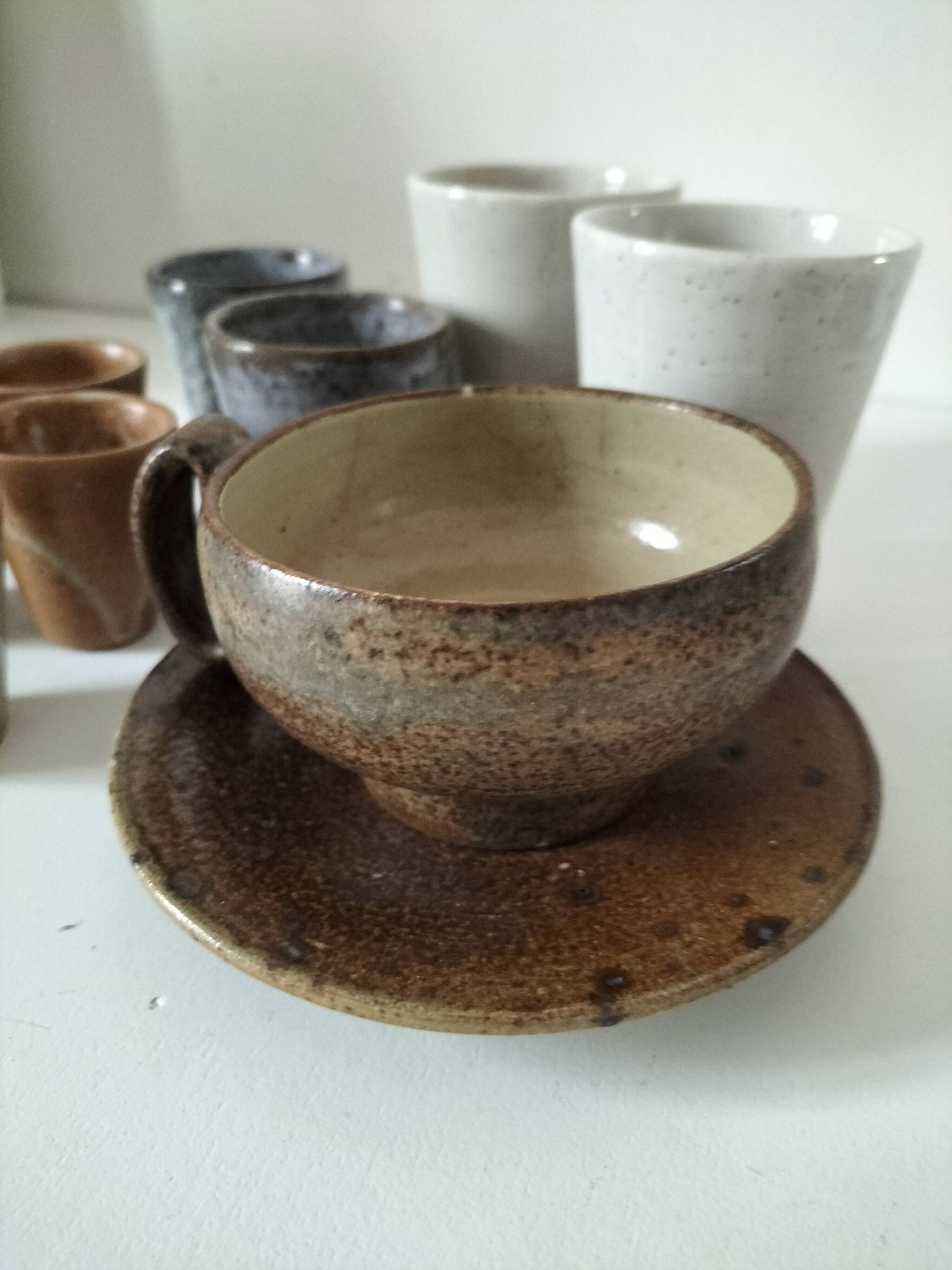 Set of 8 stoneware cups and a mug, shades of beige.