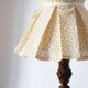 Table lamp with a carved wooden base and pleated lampshade
