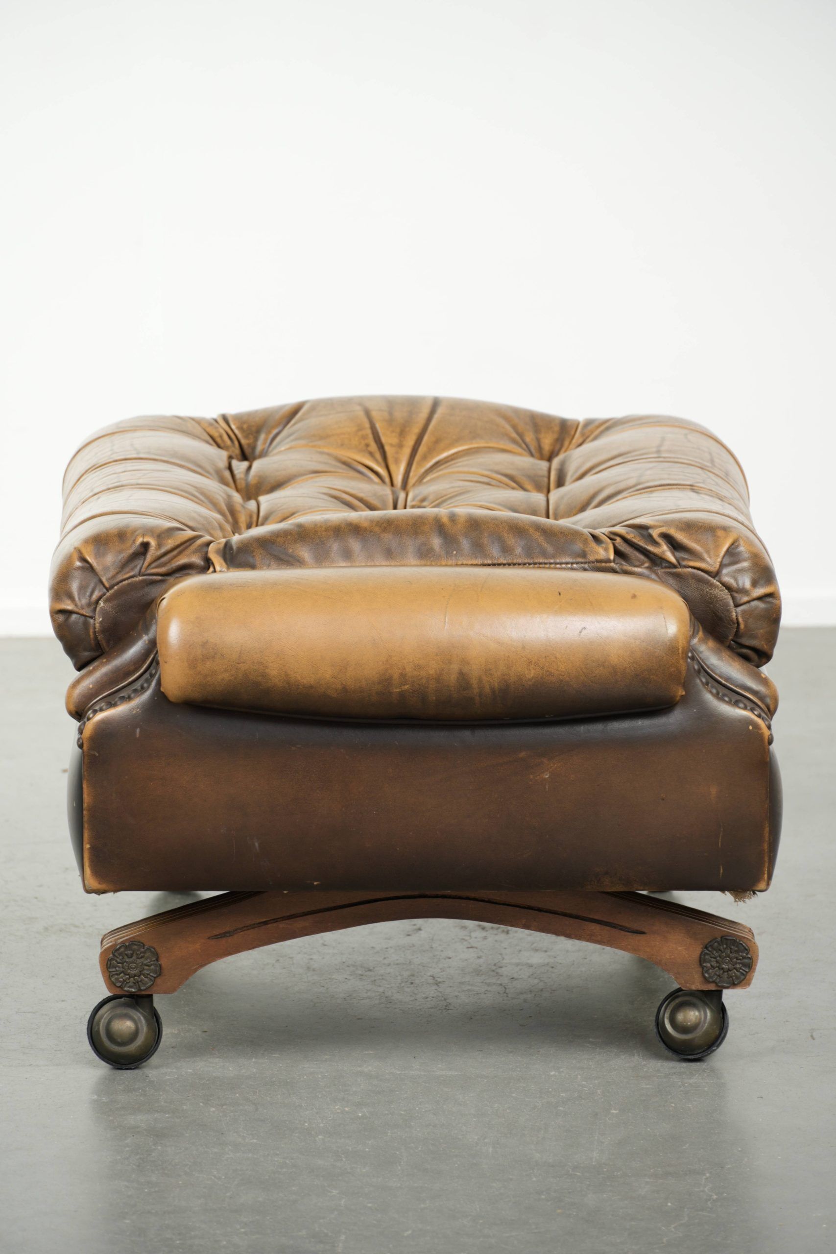 Ottoman chesterfield anglais en cuir élégant, fini avec des clous décoratifs.
