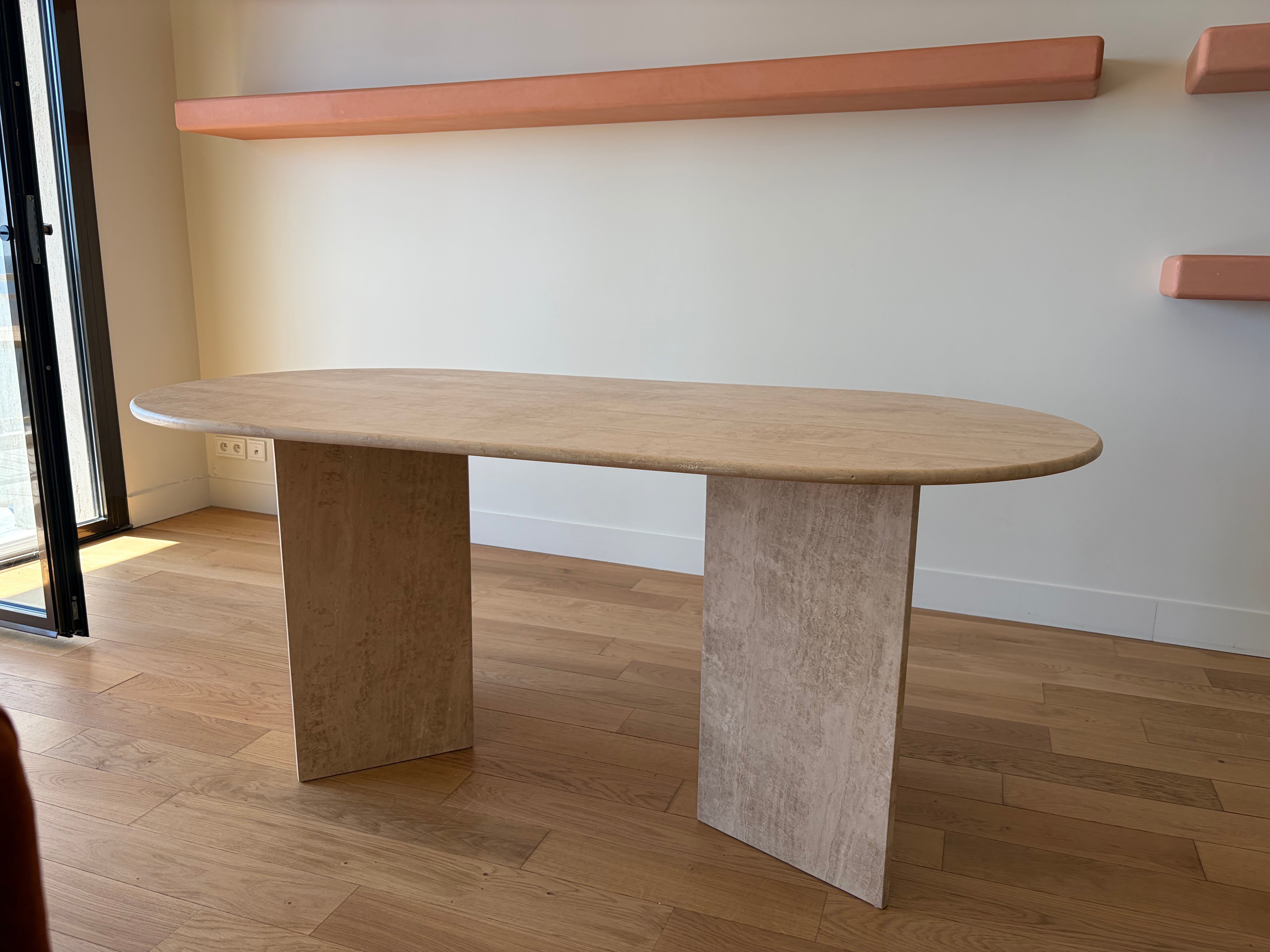 Oblong dining table in beige travertine.