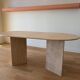 Oblong dining table in beige travertine.