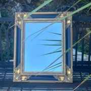 Miroir Baroque en bois doré sur fond noir.