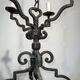 Two-tiered wrought iron chandelier with eight light arms in Gothic style.