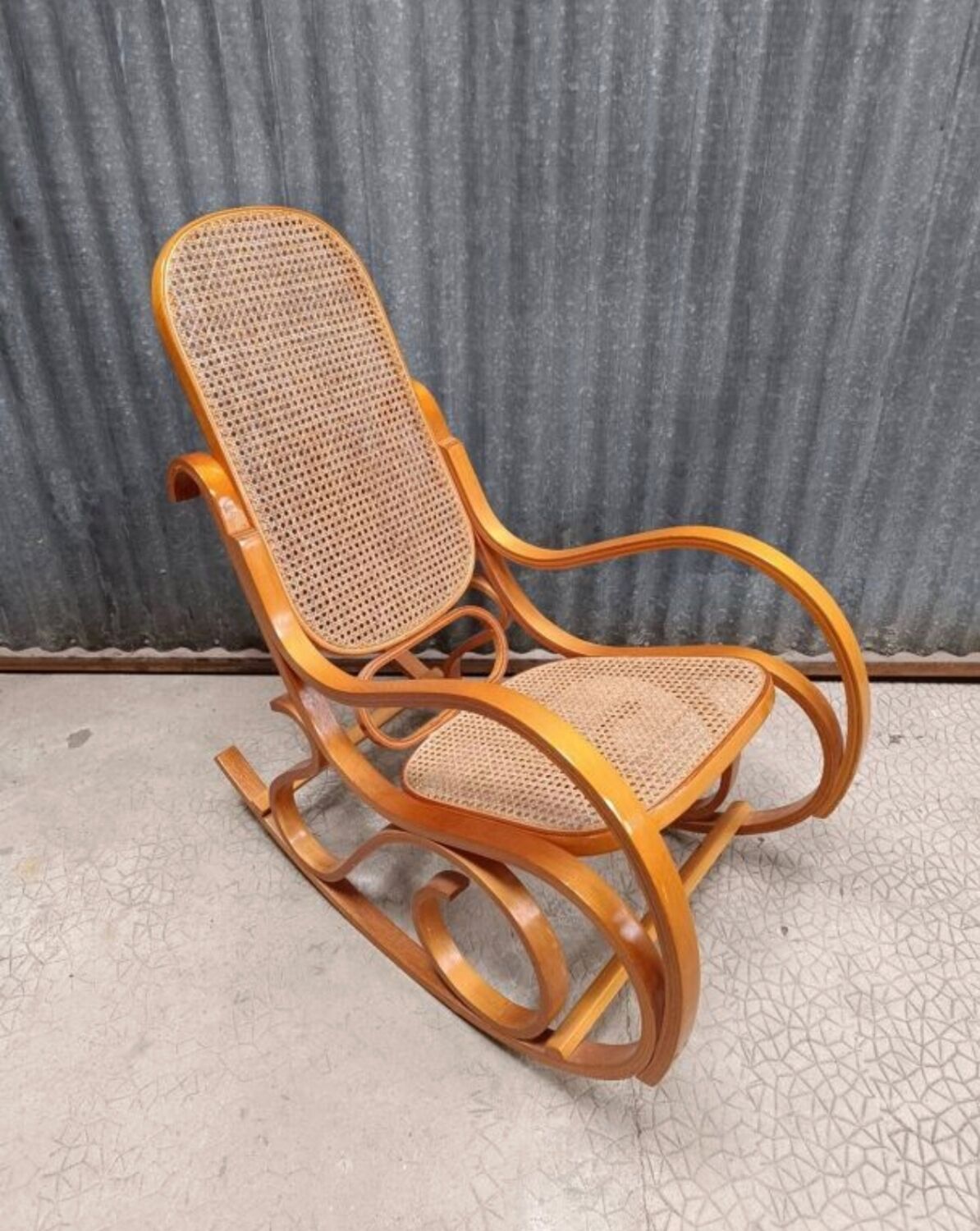 Curved wooden rocking chair with wicker cane rattan.