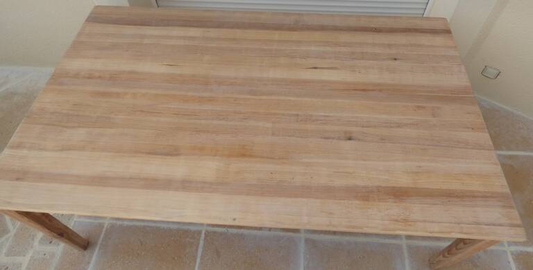 Large natural wood table with rectangular top supported by legs