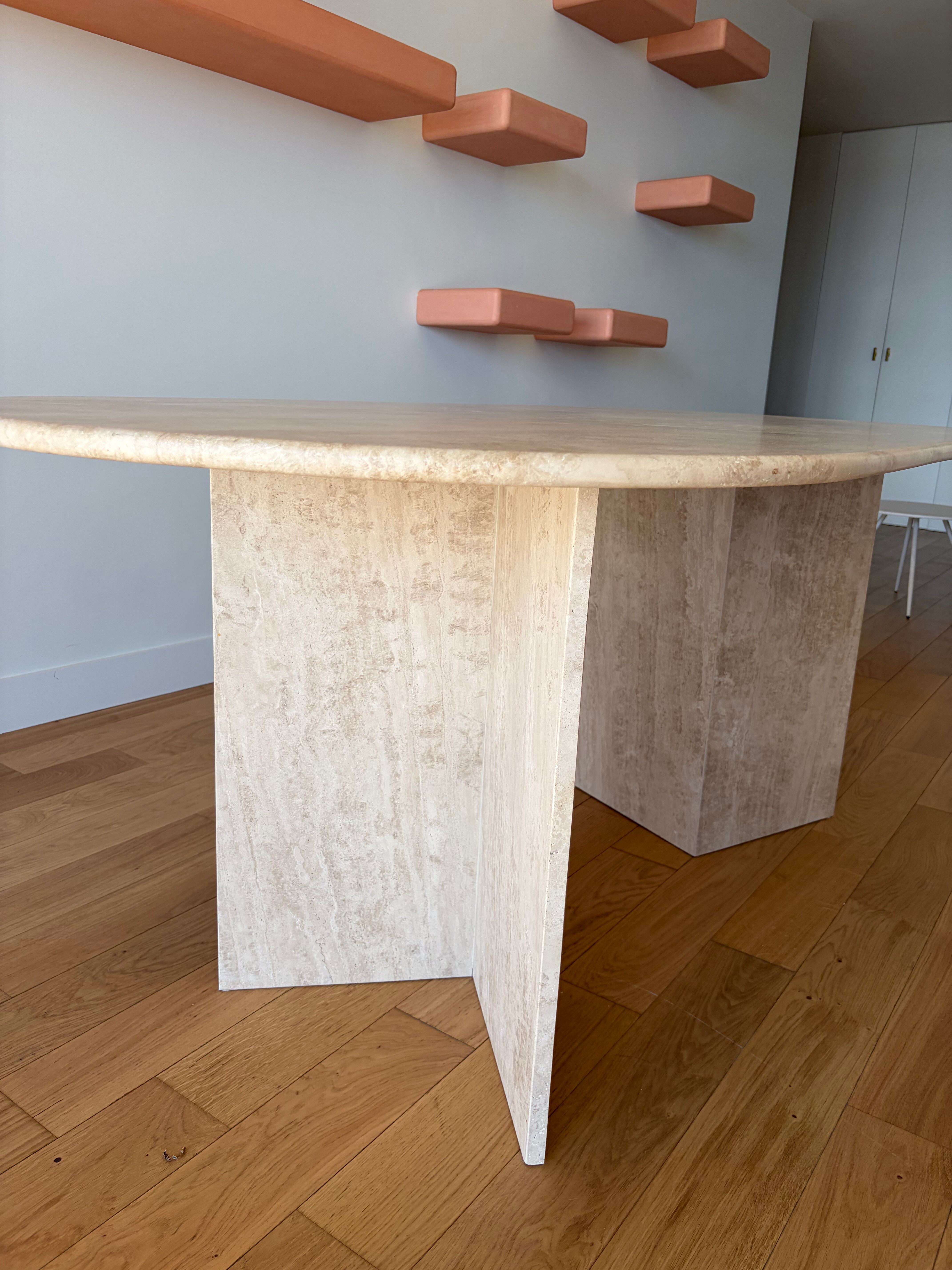 Oblong dining table in beige travertine.
