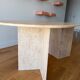 Oblong dining table in beige travertine.