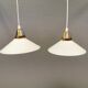 A set of hanging lamps in milky white opal glass with brass top.