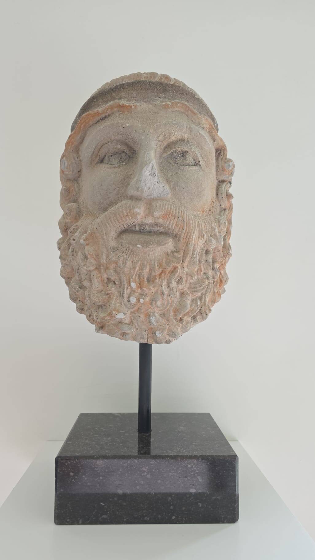 Greek god statue in stone with a marble base.