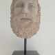 Greek god statue in stone with a marble base.