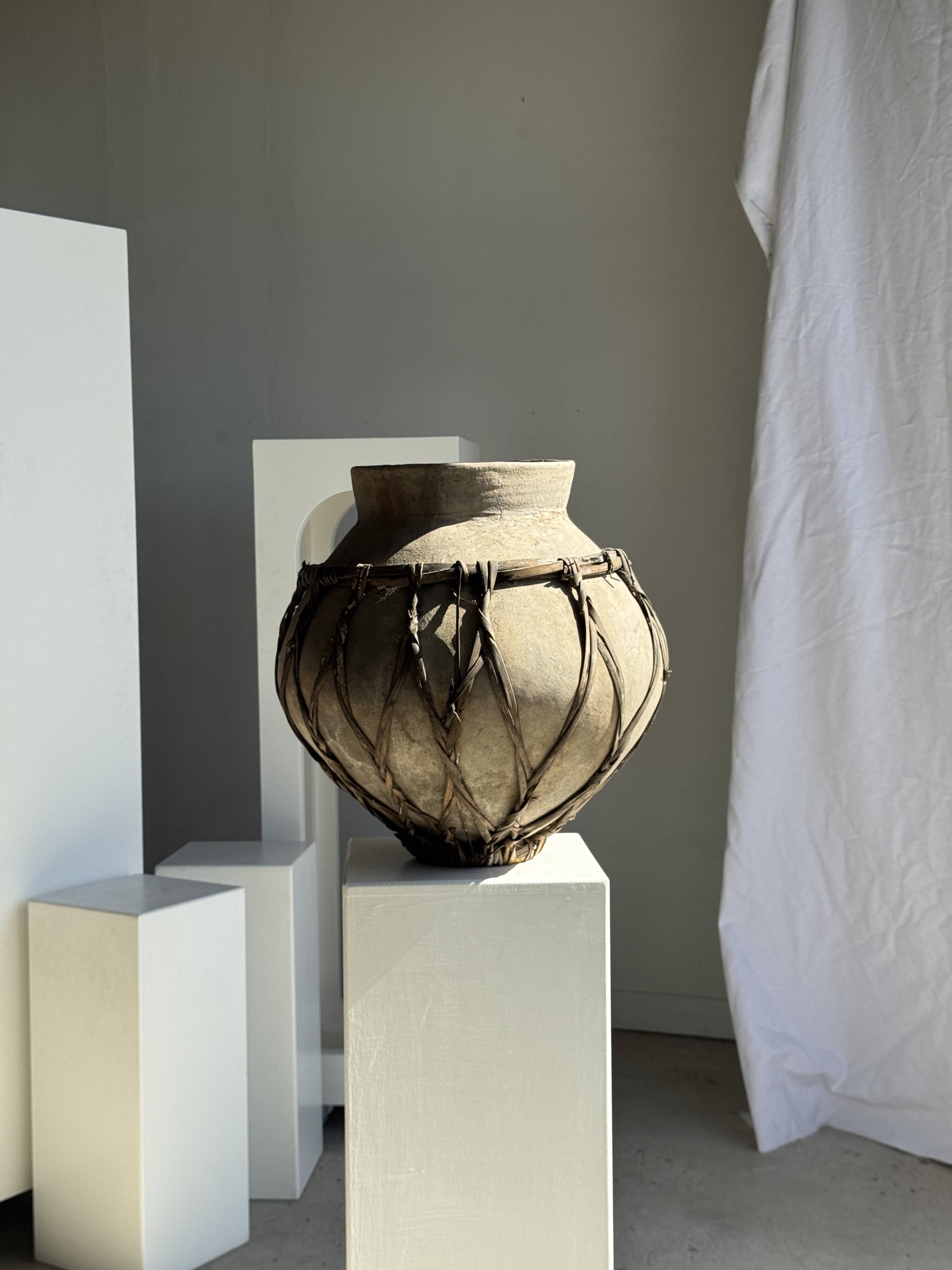Very large light grey terracotta pot with handles and rattan crossbars.