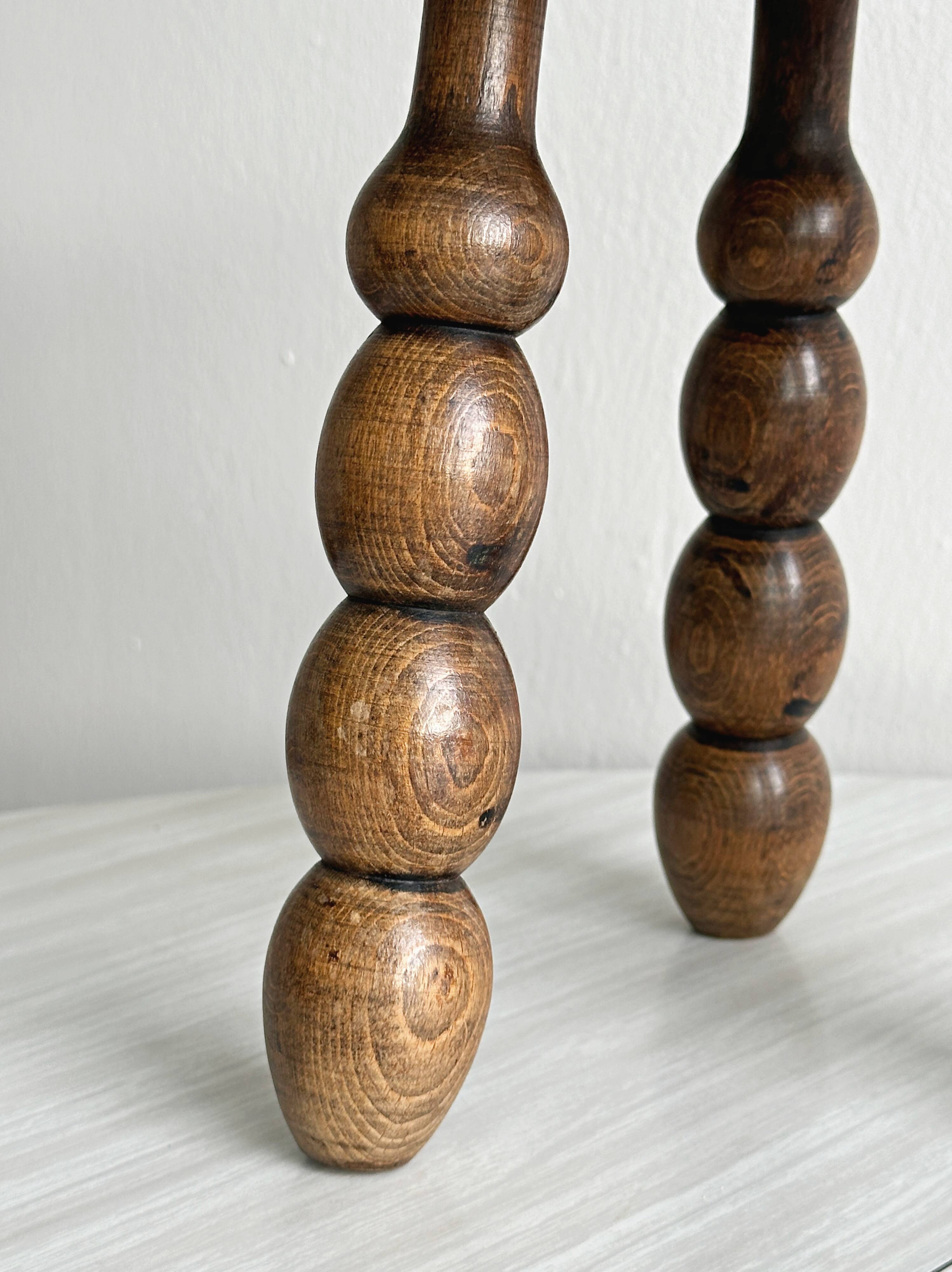Small three-legged stool made of turned wood.