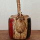 Vintage ceramic teapot with an enamel finish, rattan handle, warm tones.