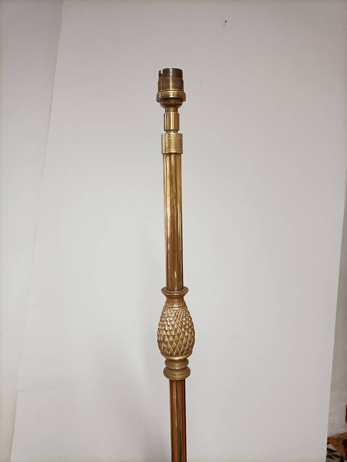 Bronze floor lamp with pine cone decoration.