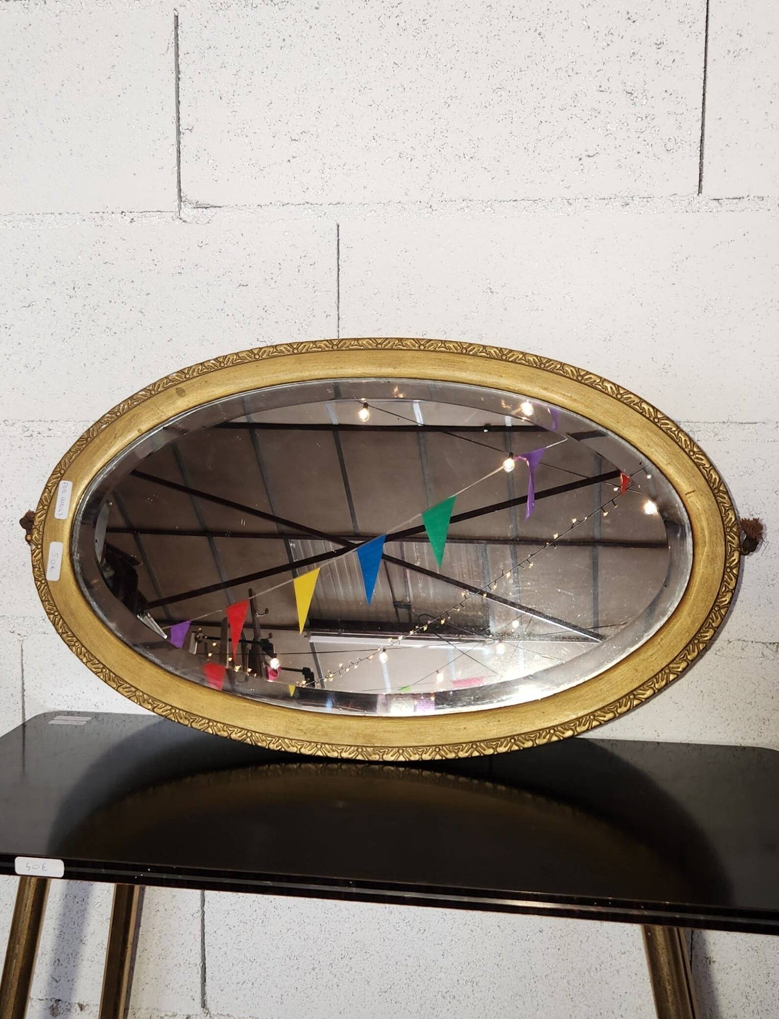 Antique oval mirror with a gilded frame, bevelled glass.