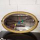 Antique oval mirror with a gilded frame, bevelled glass.