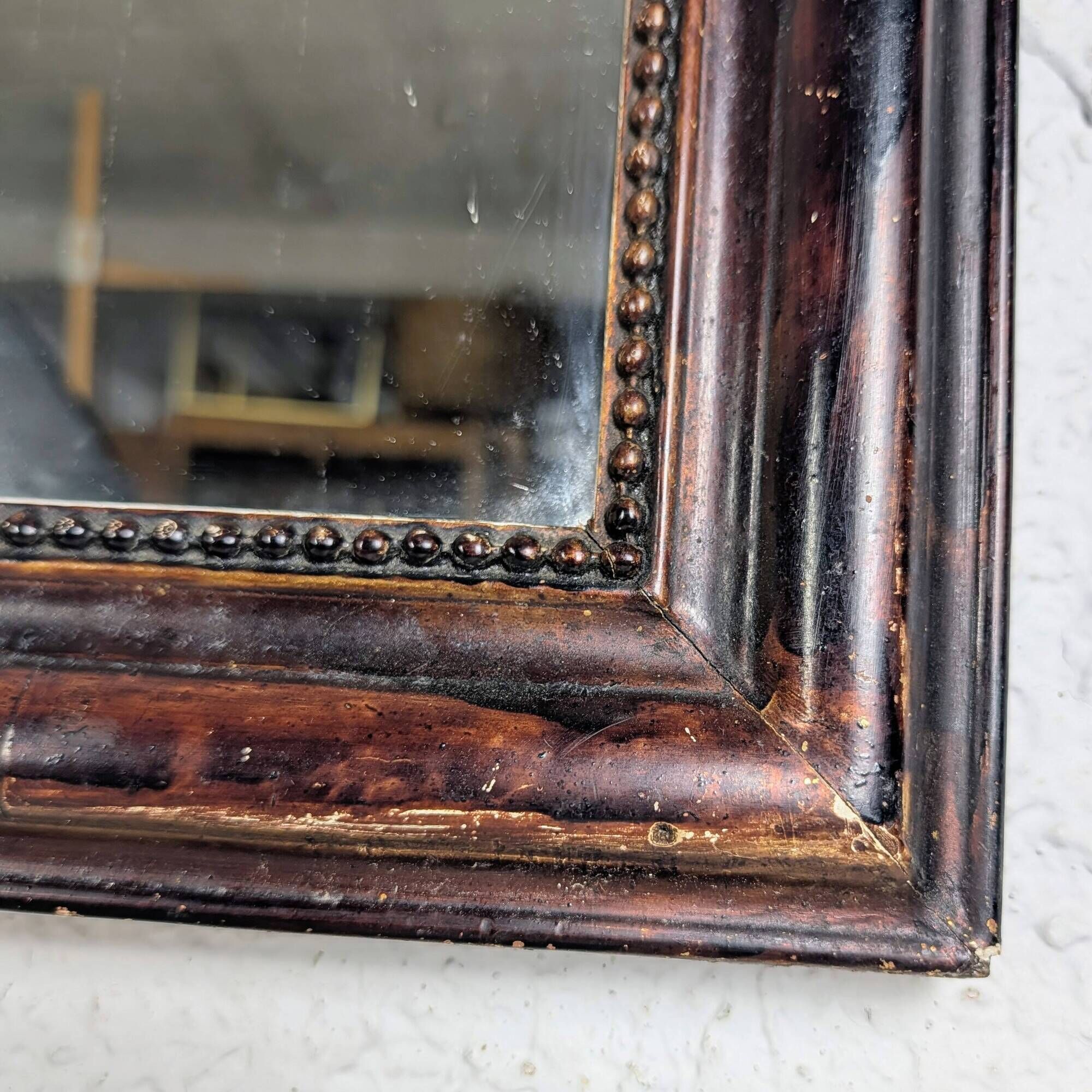 Antique Louis Philippe mirror with a patinated black frame.