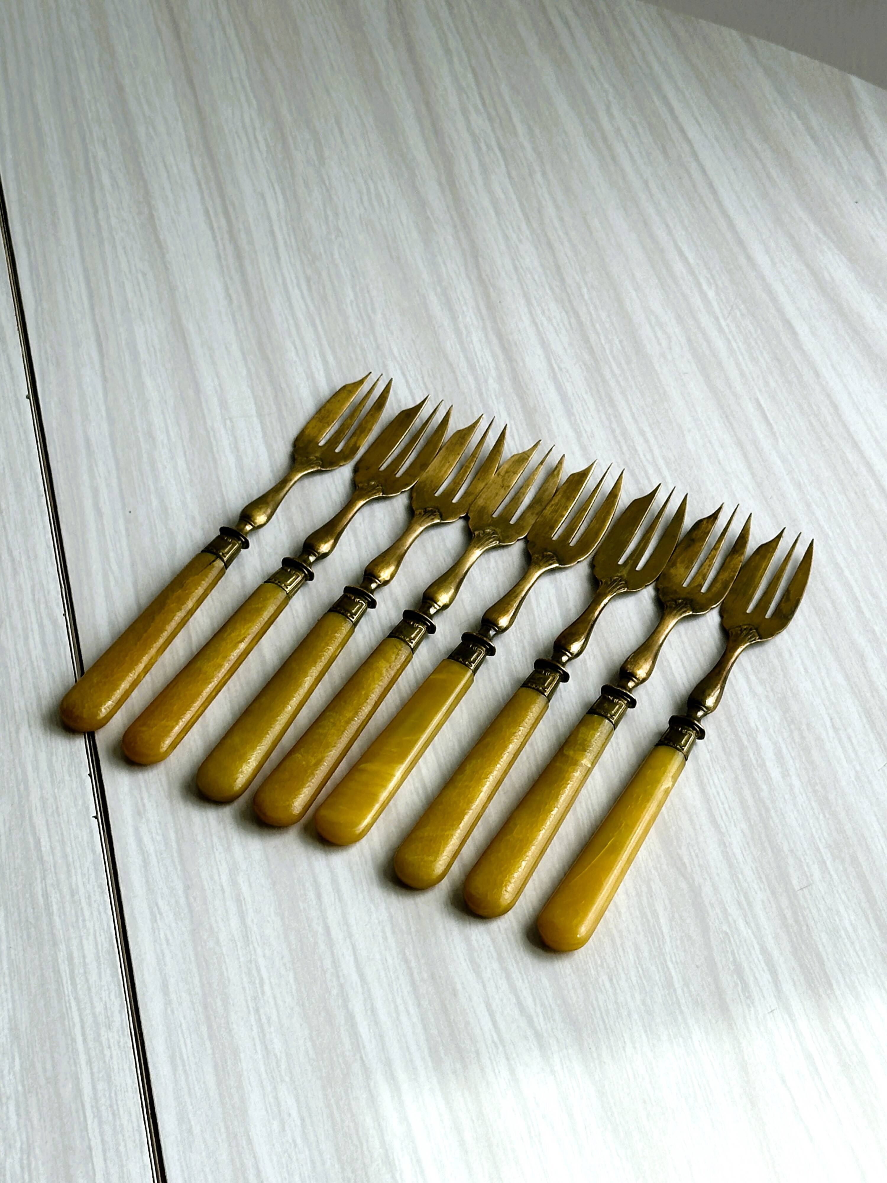 8 fourchettes à dessert vintage en métal doré et  manches en bakélite jaune.