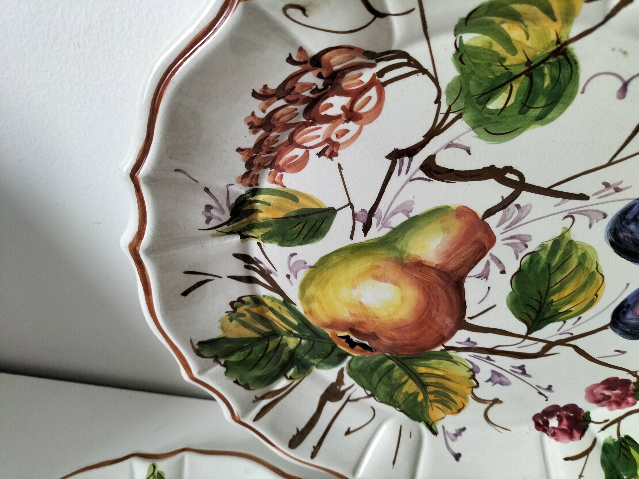 Set of three earthenware plates from Bassano, hand-painted with fruit and flower designs.
