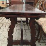 19th-century brown walnut dining table with sculpted trestle legs.
