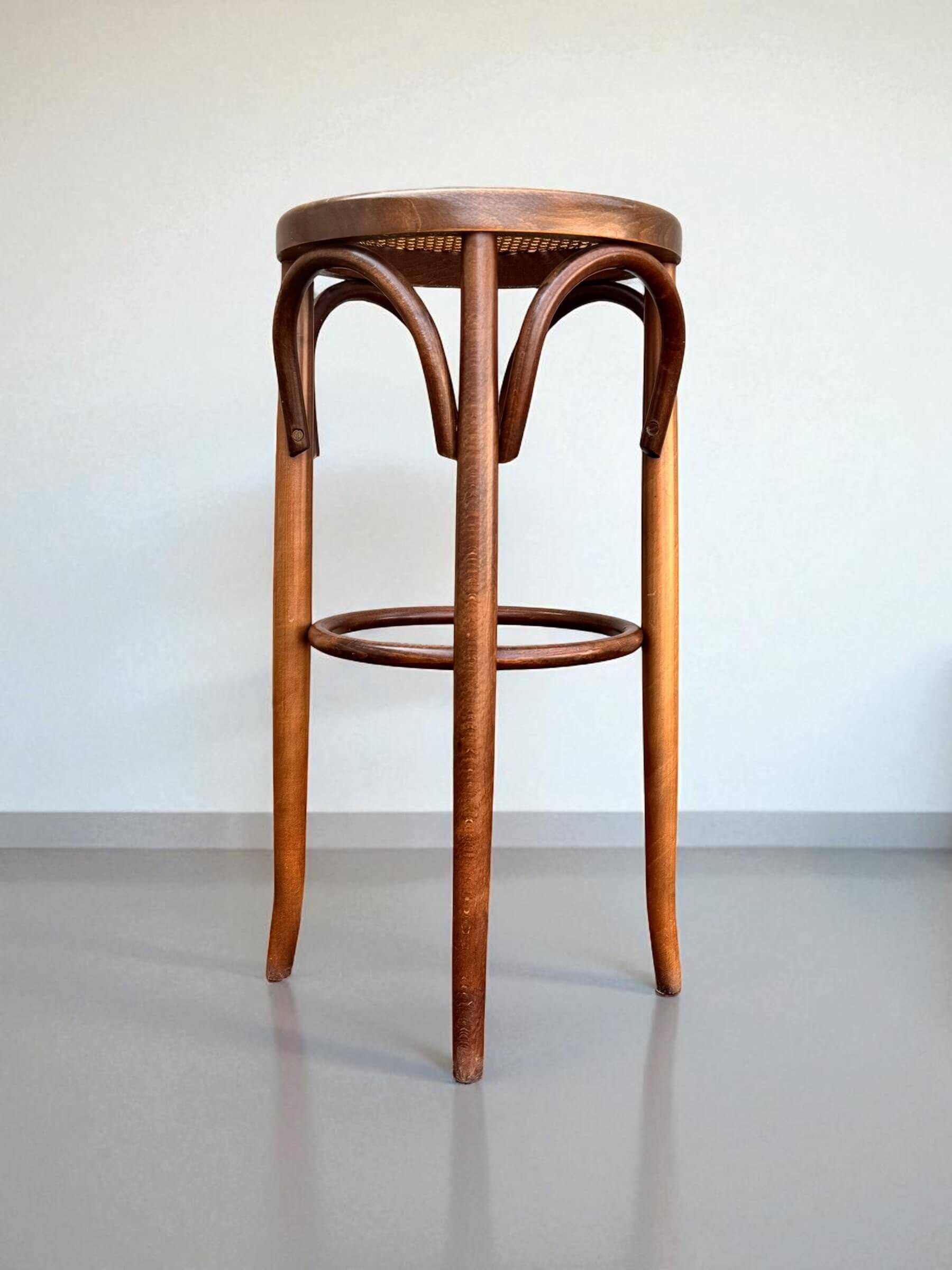 Old high stool in curved wood with caned seat