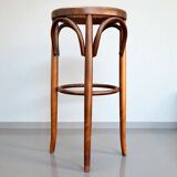 Old high stool in curved wood with caned seat