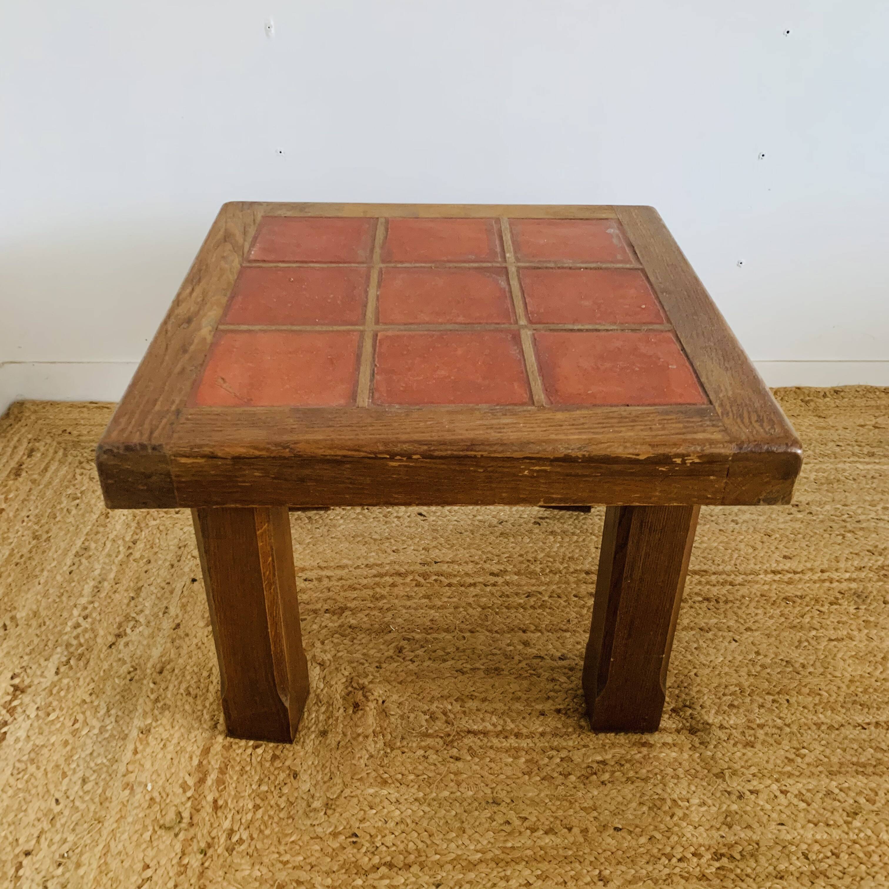 Square table with red tiles signed.
