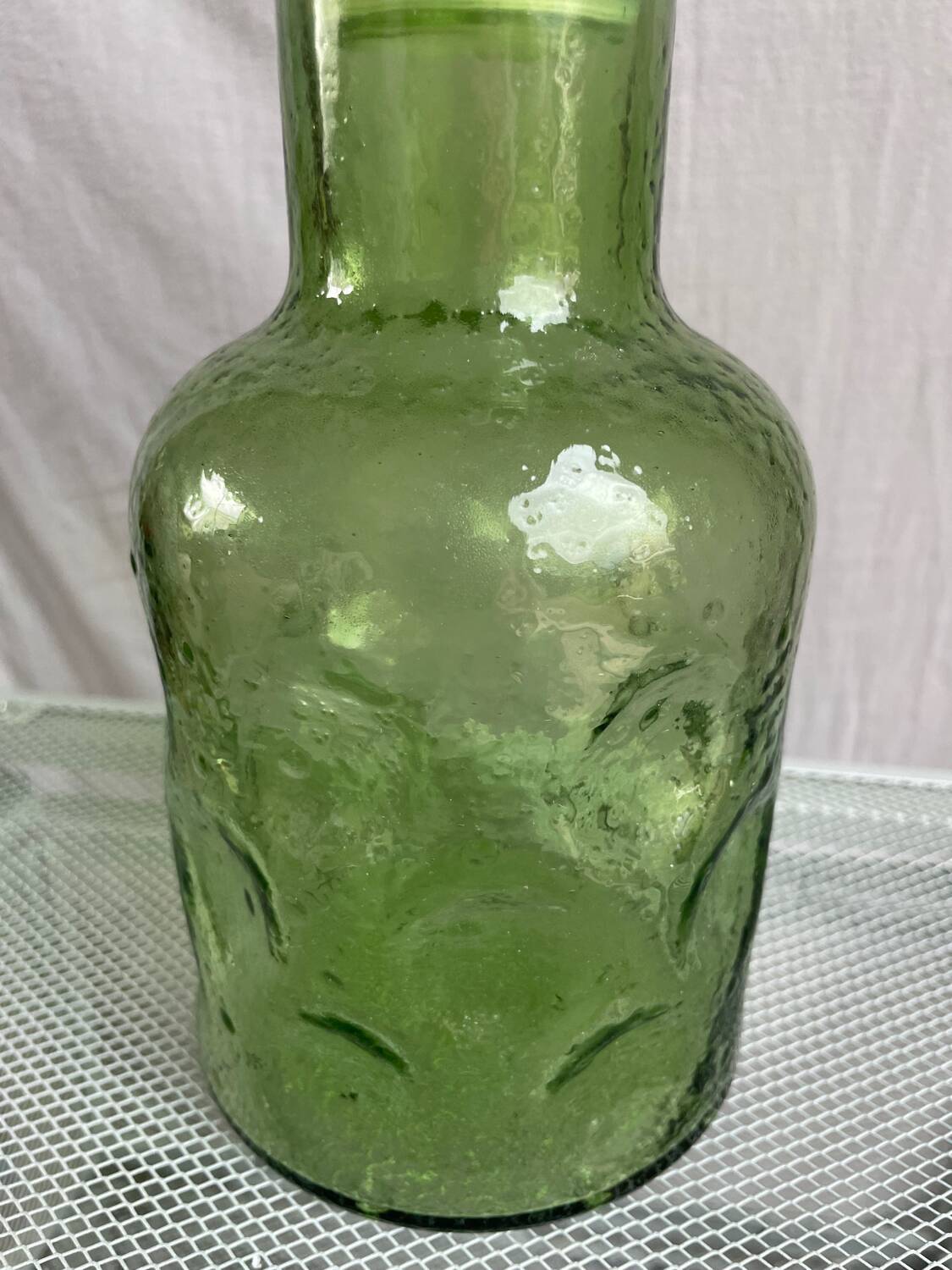 Green glass bottle with craters