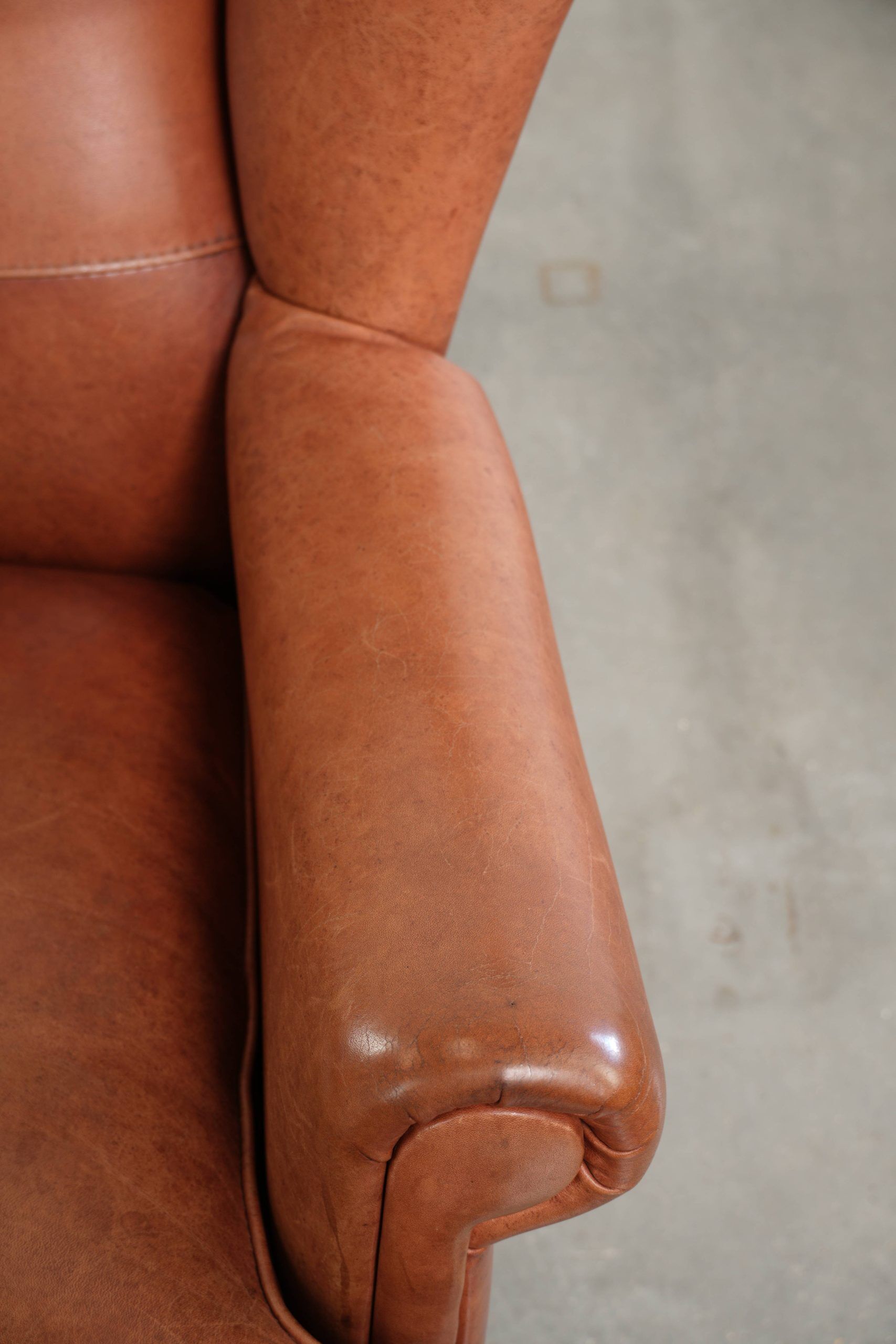 Light cognac-coloured cow leather wingback armchair with matching piping