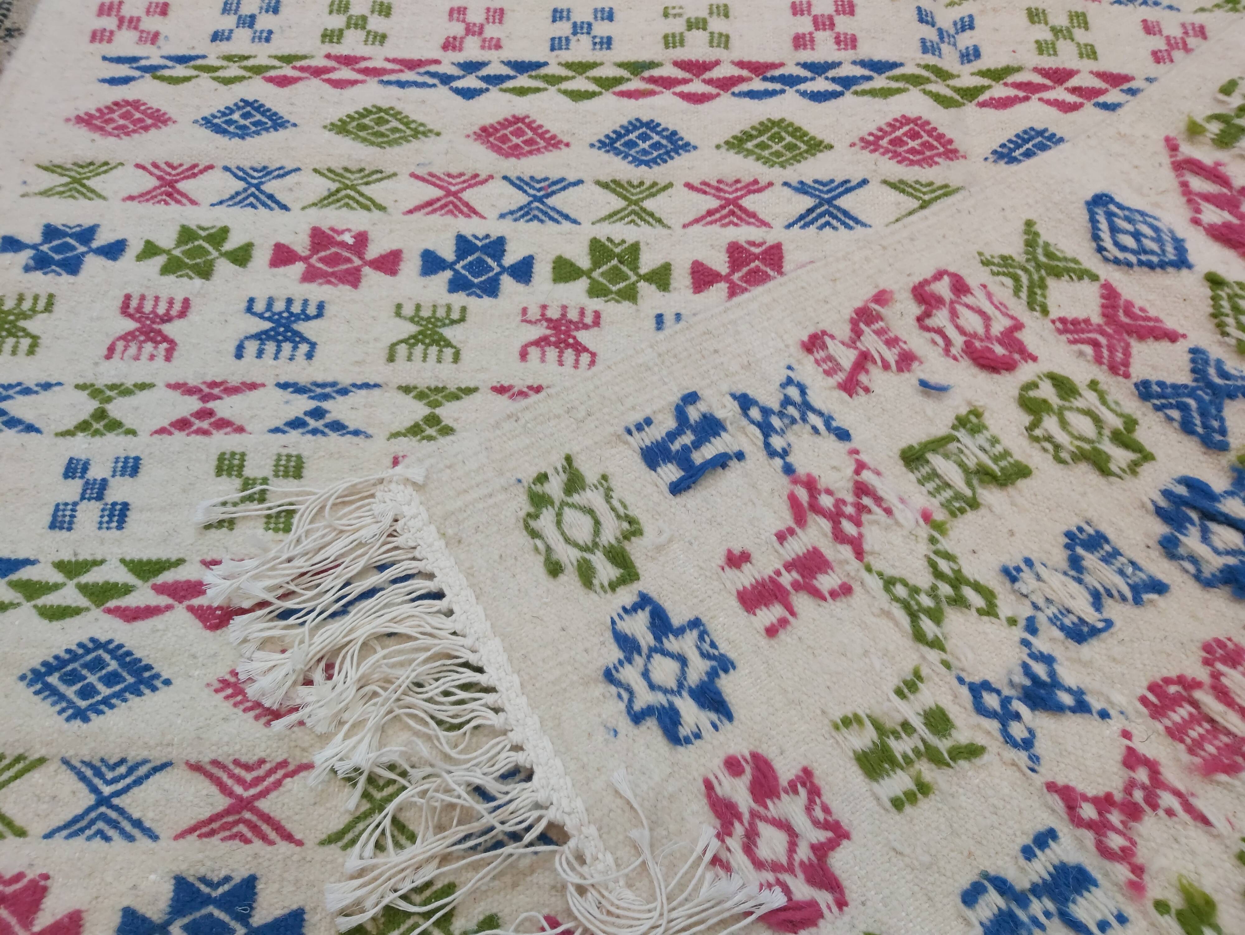 White carpet with Berber motifs pink green and blue