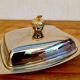 Vintage silver-plated metal butter dish with a gold tassel knob