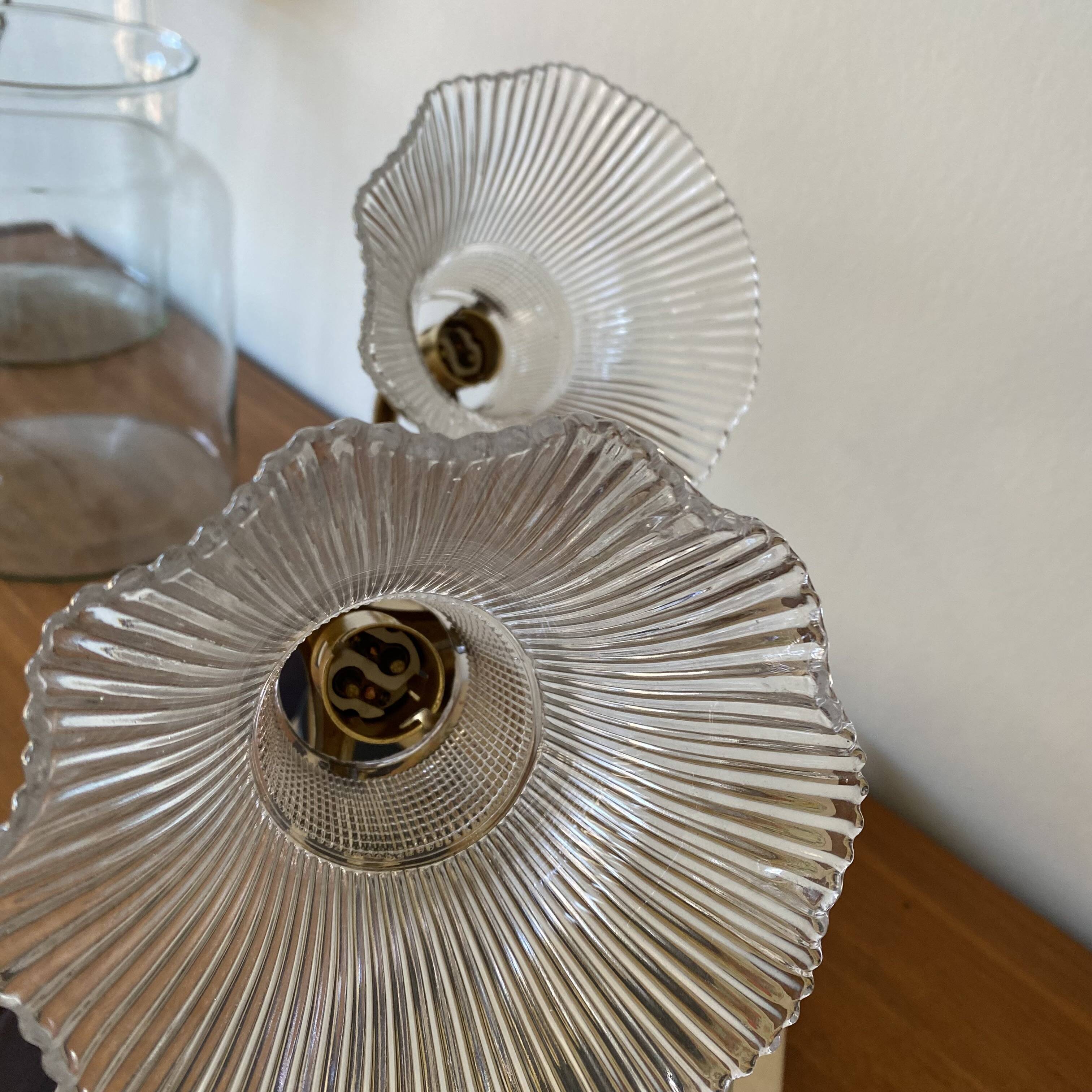 Pair of brass swan neck wall lights with transparent glass shades.