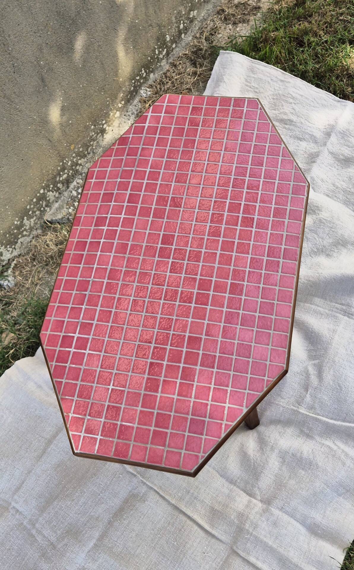 Small Scandinavian side table with wood and pink tiles, with tapered legs.