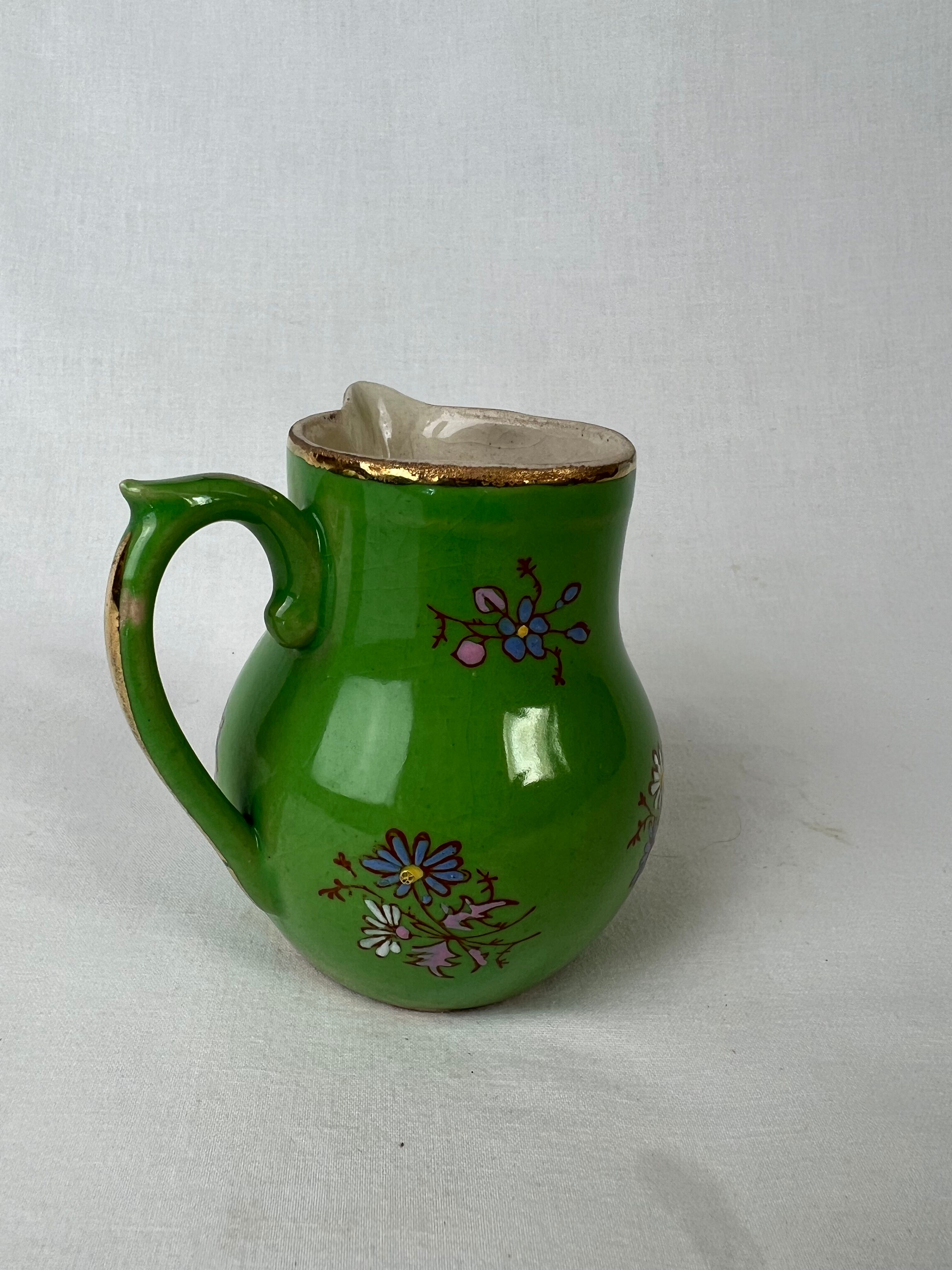 Green milk jug with enamelled flowers