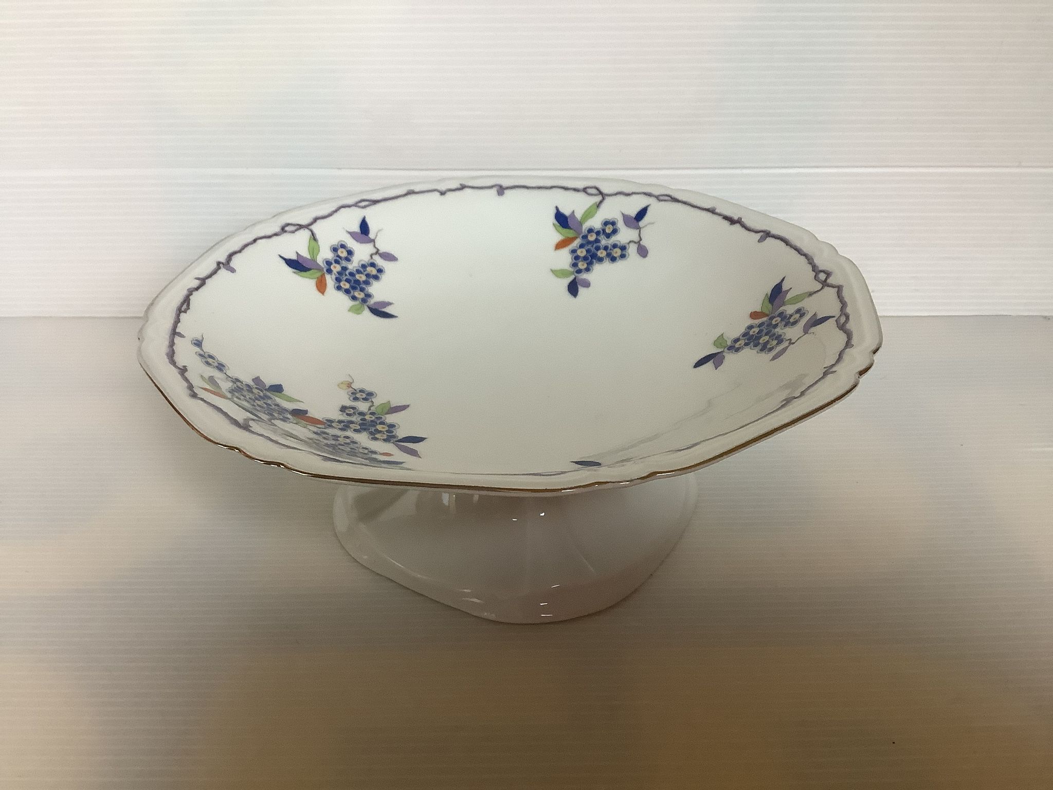 Old shower tray with silver trim and forget-me-not flowers.