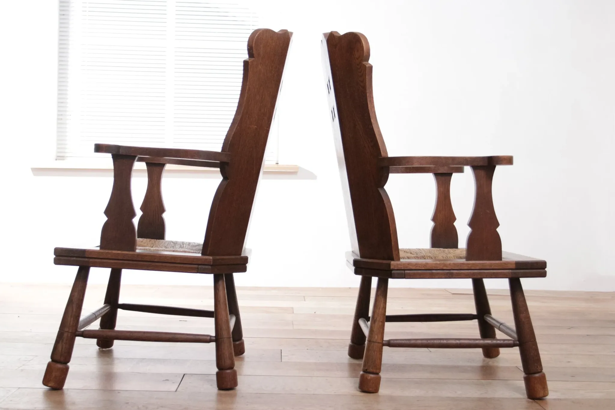 Pair of brutalist oak lounge chairs with rush seats, circa 1935